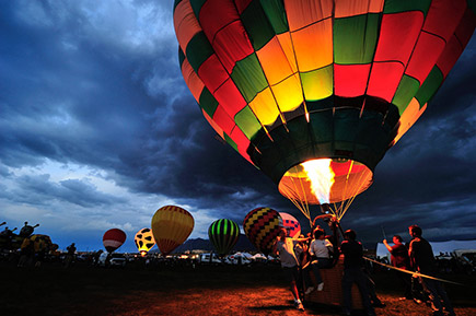 Learn how to take amazing photos at Nikon School Photo of a hot air balloon with people standing around it in the foreground in low light