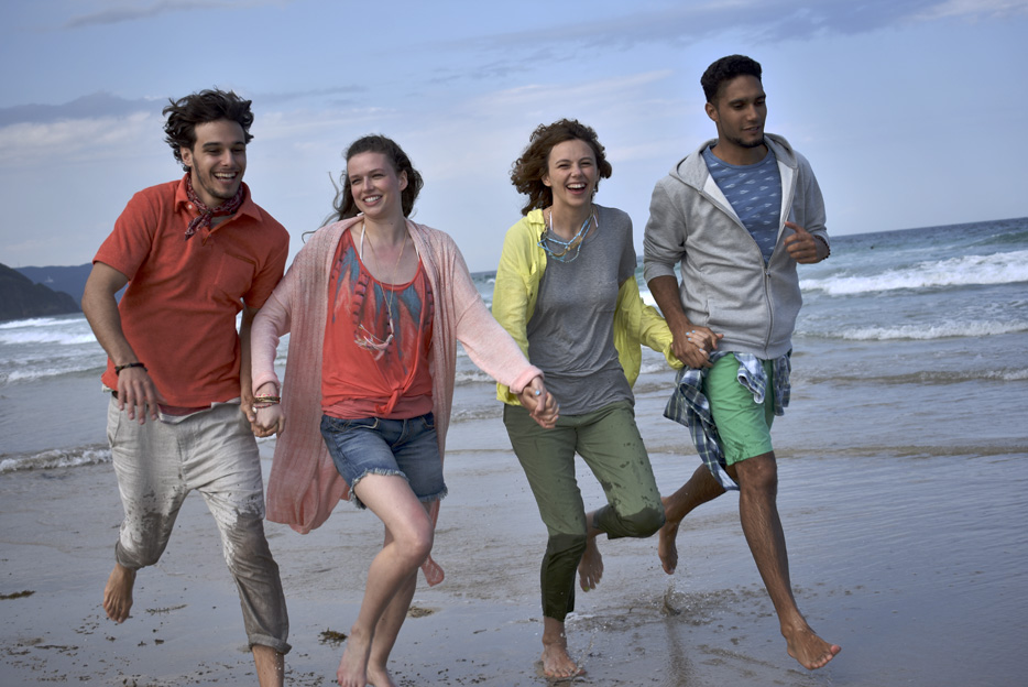 D3400 photo of two couples running on the beach, with the ocean in the background