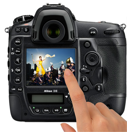 Photo of the rear of a D5 DSLR with an image of a woman leading a marching band and a hand touching the LCD showing touchscreen functionality