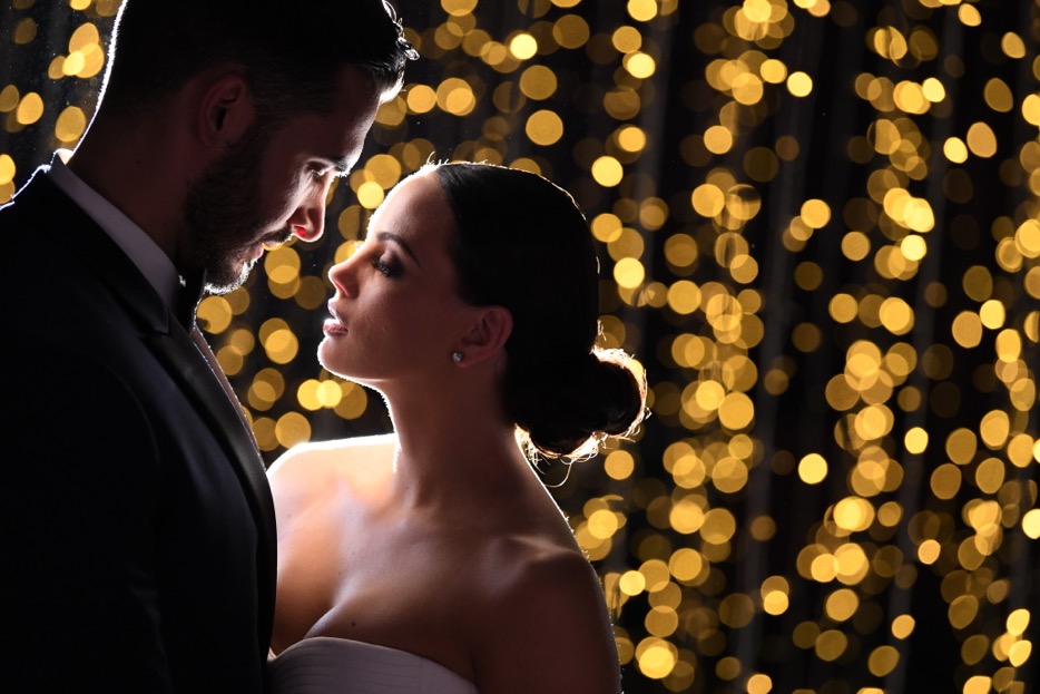 D850 DSLR arka planda bokeh ışıkları olan bir gelin ve damat fotoğrafı