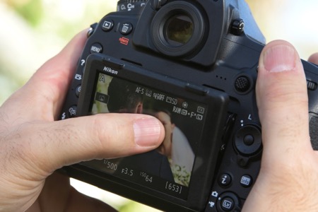 Photo of a photographer's hands on the D850 using the touchscreen LCD
