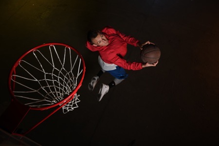 D850 DSLR photo of a basketball player jumping for a dunk in low light