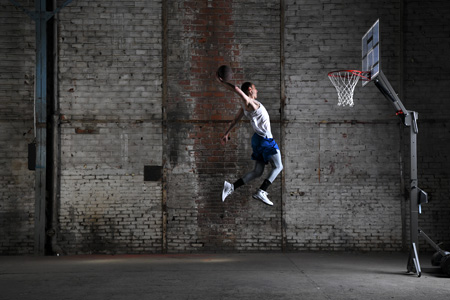 D850 DSLR photo of a basketball player in air dunking the basketball