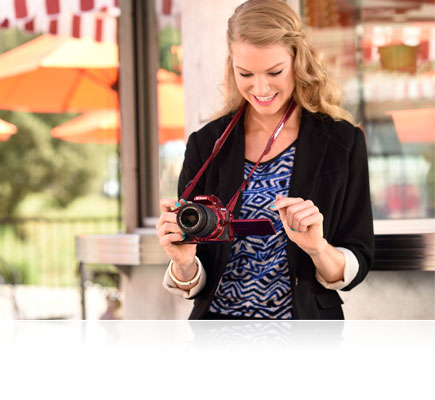 D5500 photo of a woman with a red D5500 around her neck looking at the LCD