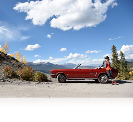 D5500 photo of a woman leaning on an a red convertible car in the desert under a blue sky