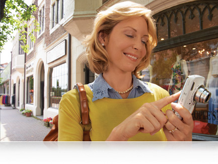 photo of a woman using the touchscreen of the COOLPIX S800c on a city street 