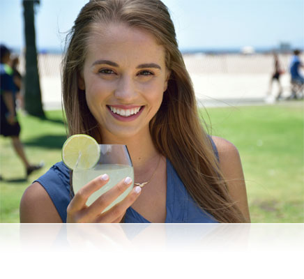 Nikon D5300 portrait of a woman holding a drink in her hand, outdoors with the beach in the background