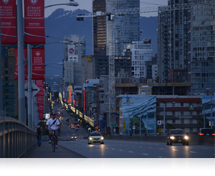 Le zoom AF-S NIKKOR 70-200mm f/4G ED VR offre cinq niveaux de stabilisation d’image VR photo d’une rue d’une grande ville au crépuscule avec des montagnes en arrière-plan