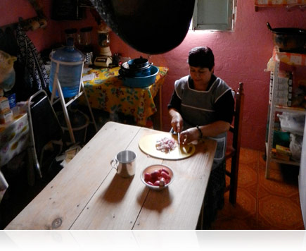Low-light photo of a woman preparing food at her kitchen table