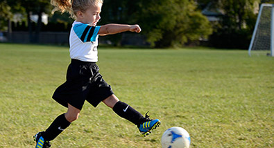 Learn how to freeze action Photo of a young girl playing soccer on a field, kicking a soccer ball