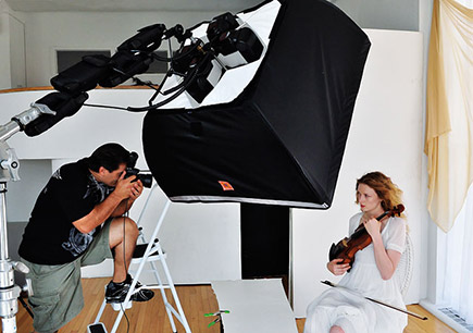 Learn advanced techniques at Nikon School Photo of a photographer shooting a woman holding a violin, in a studio with a softbox