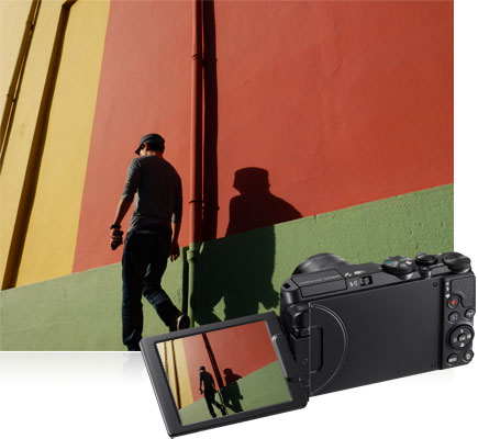 COOLPIX S9900 photo of a man walking next to a colorful wall, inset with the image on the LCD of the camera