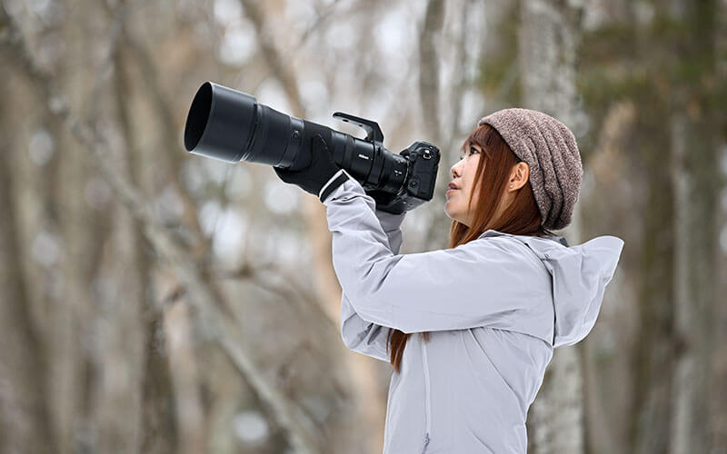 photo of a woman holding a camera and NIKKOR Z 180-600mm f/5.6-6.3 VR lens