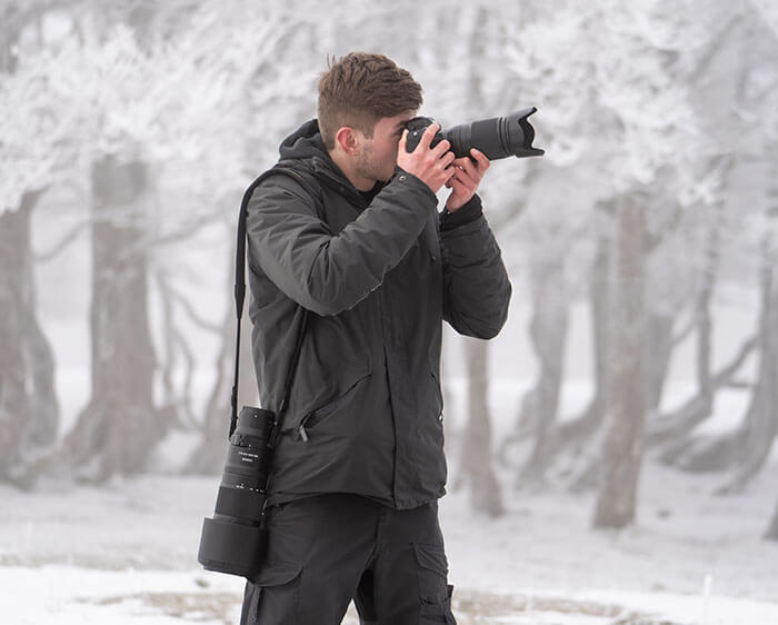 photo of a photographer holding a camera and NIKKOR Z 70-180mm f/2.8 lens