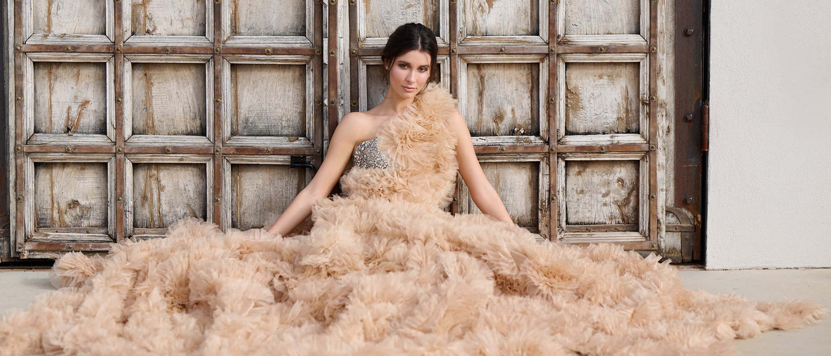 photo of a model in a fluffy dress in front of textured doors, taken with the NIKKOR Z 85mm f/1.2 S