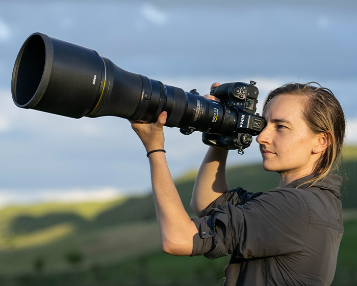 Photo of a woman looking through the viewfinder of a camera with the NIKKOR Z 800mm f/6.3 VR S lens attached
