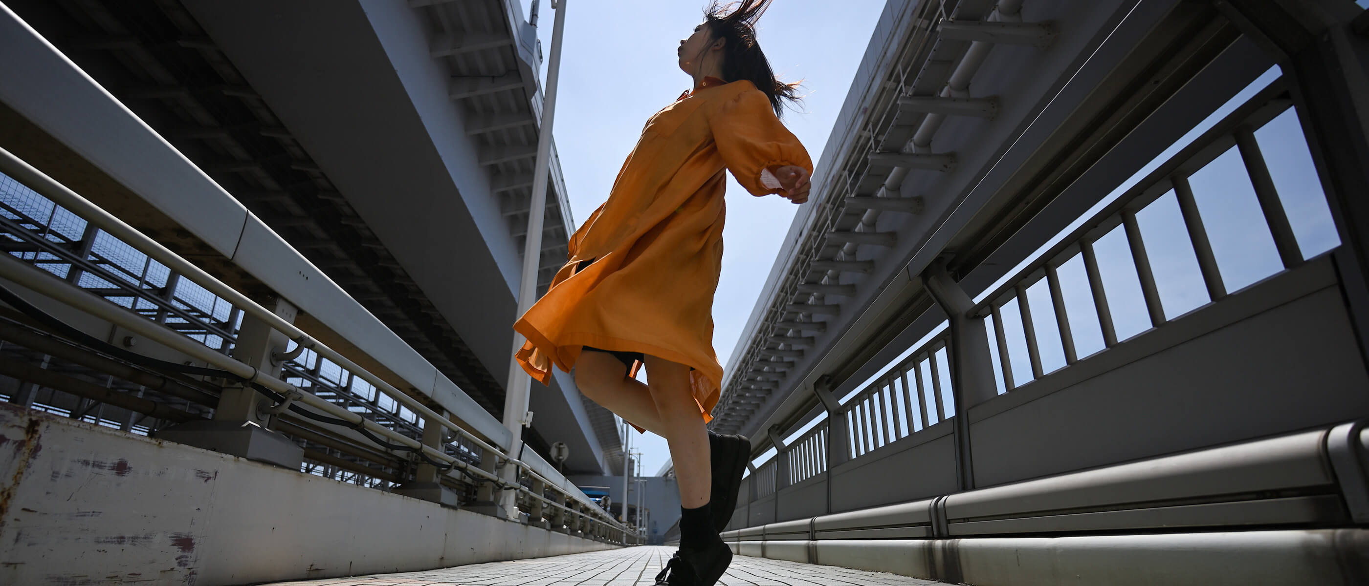 Photo of a woman in an orange dress outdoors taken with the NIKKOR Z 17-28mm f/2.8 lens