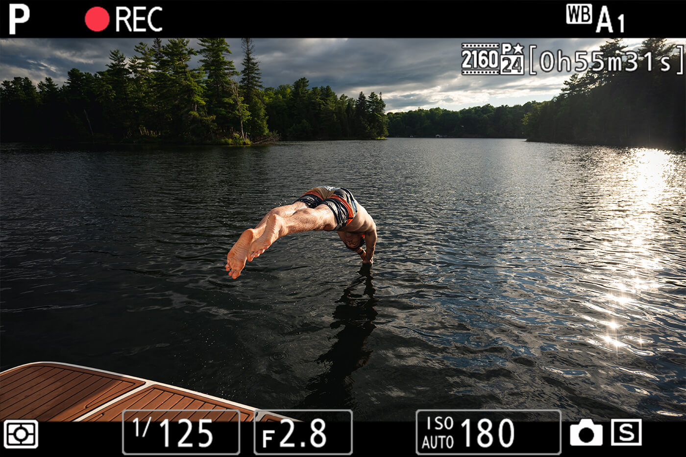 photo of a man diving into a lake, with the camera's record button graphic and other viewfinder overlay items, taken with the NIKKOR Z 17-28mm f/2.8 lens