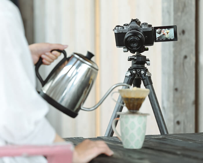 Photo of a woman pouring coffee, being captured on video by the Z fc and NIKKOR Z 28mm f/2.8 (SE) lens on a tripod