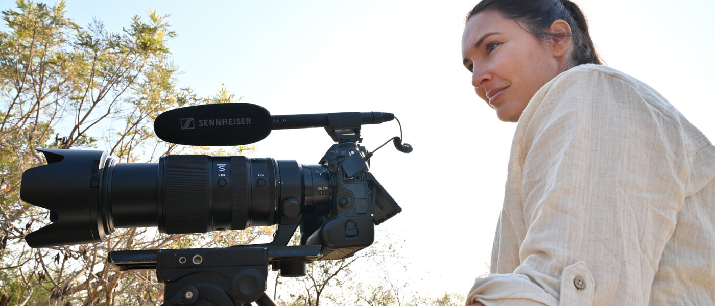 photo of a videographer with the NIKKOR Z 100-400mm f/4.5-5.6 VR S lens on a camera with mic on a tripod