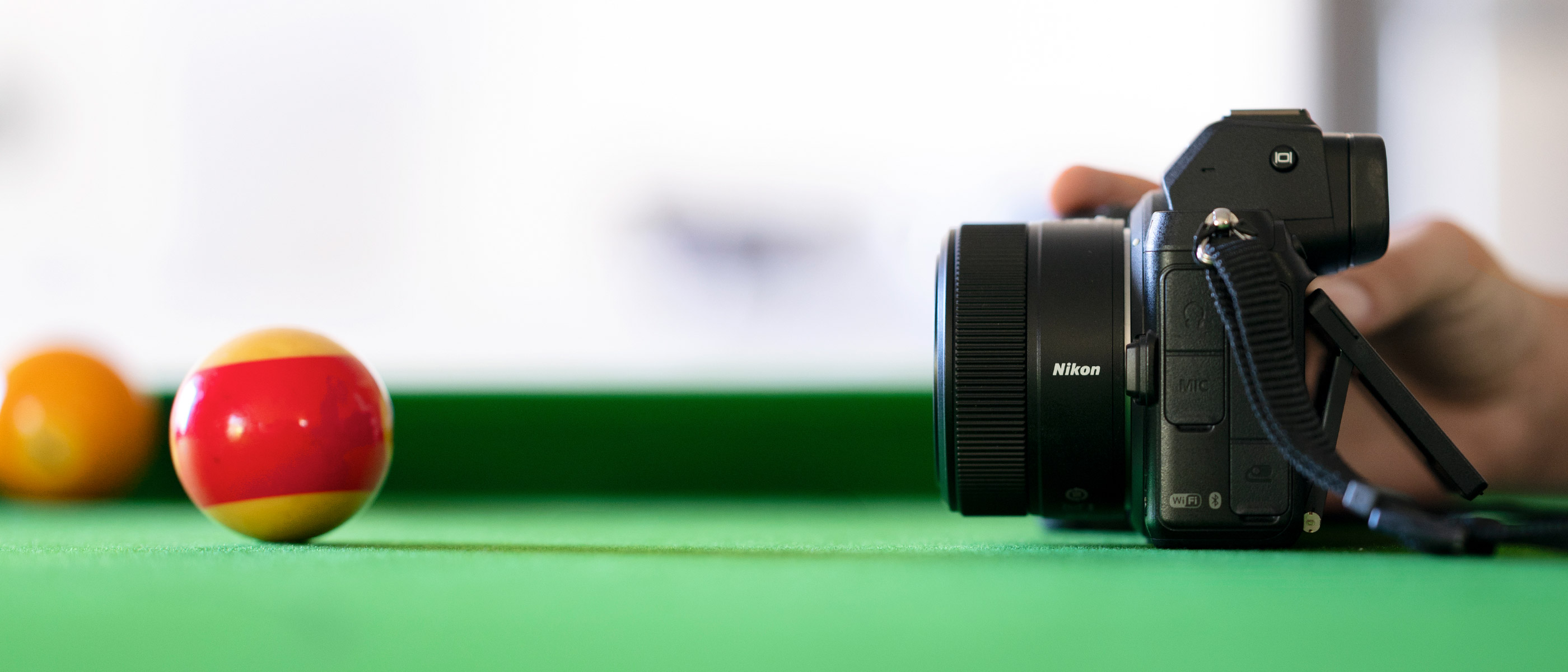 Photo of a Nikon Z camera with NIKKOR Z 28mm f/2.8 lens on a pool table