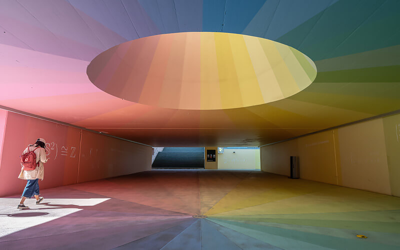 interior photo of a room, in rainbow colors, with a woman walking through it taken with the NIKKOR Z 14-24mm f/2.8 S lens