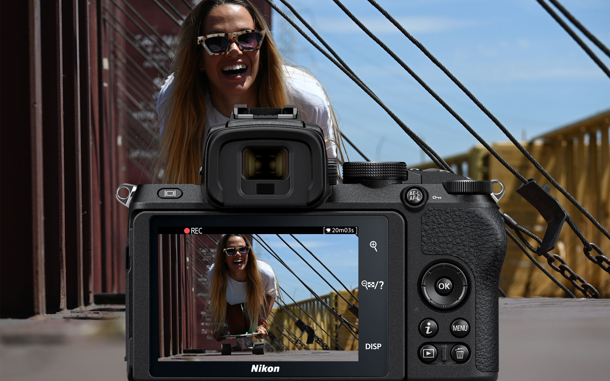 Photo de l'écran LCD arrière du Z 50 et Nikkor Z DX 50-250 mm f / 4.5-6.3 VR VIDE d'enregistrement d'une femme, avec la scène visible en arrière-plan de l'image