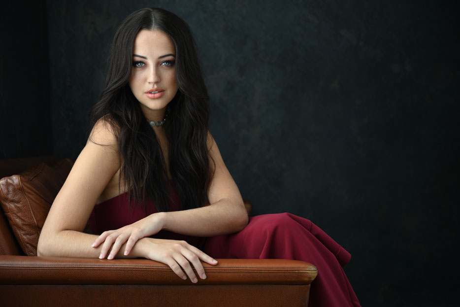 photo of a model sitting in a chair, looking at the camera, taken with the Z 7 and NIKKOR Z 24-70mm f/4 S lens