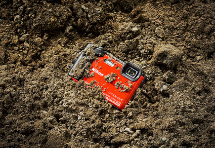 Photo of the COOLPIX W300 half buried in dirt