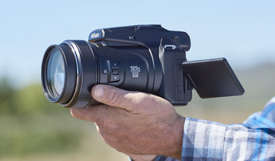 Photo of a man's hands holding the COOLPIX P1000