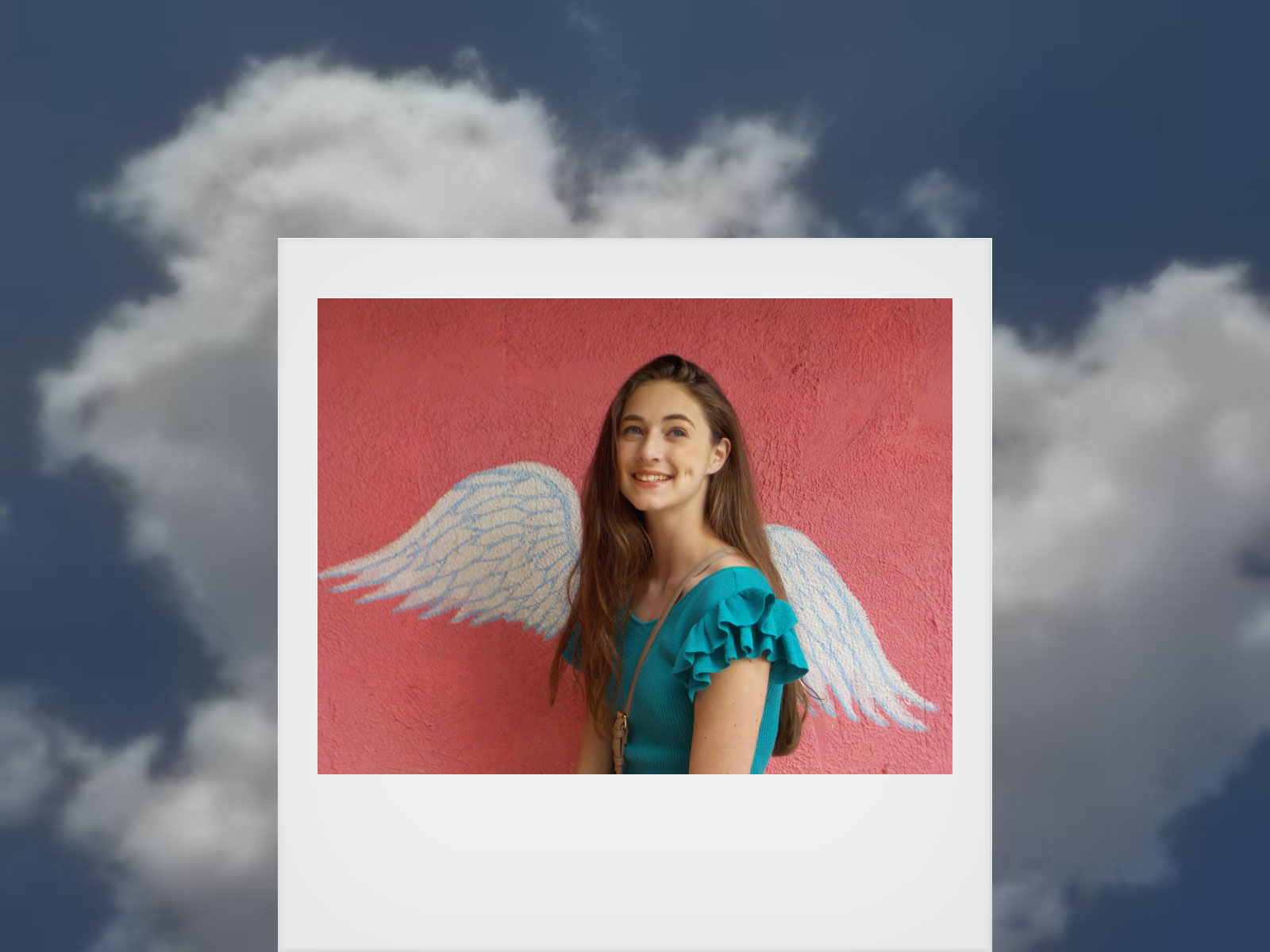 Photo of a girl with wings on the wall behind her and a sky behind the photograph, taken with COOLPIX W150