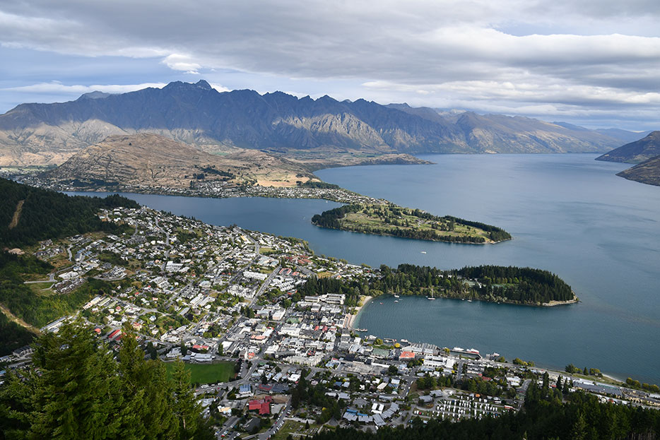 Photo of a landscape including a city and waterway, with mountains in the background