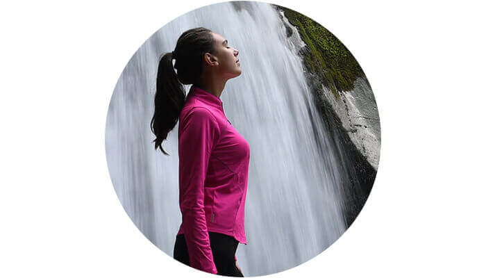 D7500 photo of a woman in a pink sweater with a waterfall behind her