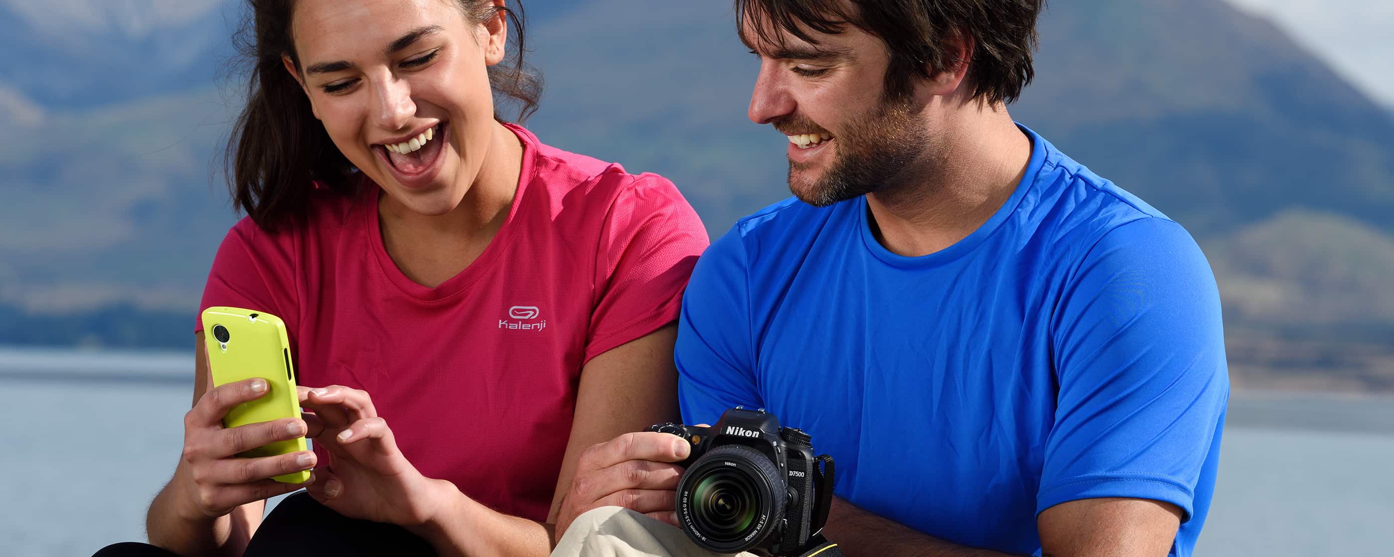 photo of a woman holding a smartphone and a man holding the D7500