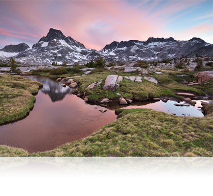 Nikon D750 photo of a colorful landscape with mountains, grass, rocks, water and a colorful sky