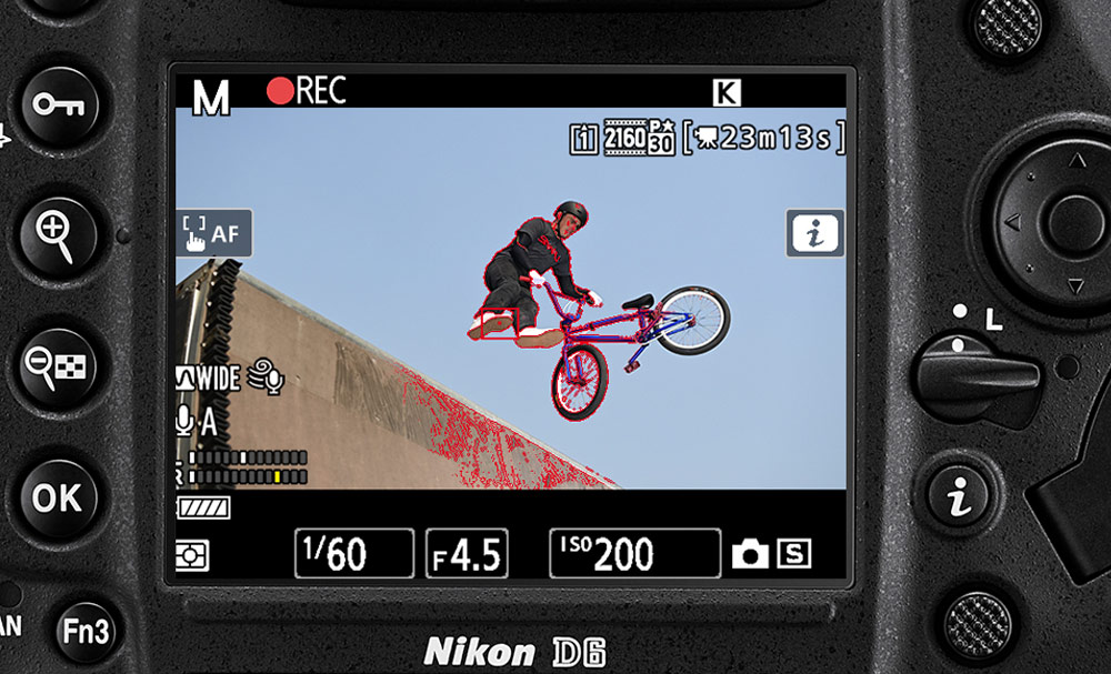 D6 DSLR photo of a bike rider in air above a ramp, on the LCD of the D6 DSLR showing focus peaking in red