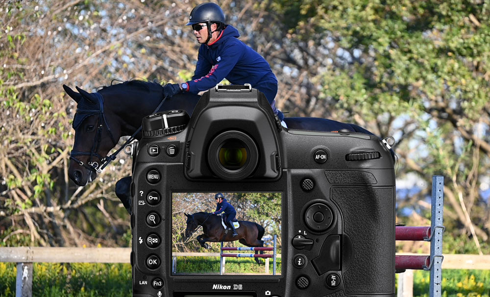 D6 DSLR photo of a horse jumping on a steeplechase course, with the camera body overlayed in front of the image, and the photo on the LCD