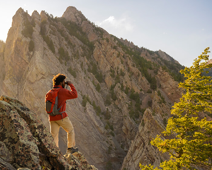 Photo of a man standing in the mountains, looking through binoculars
