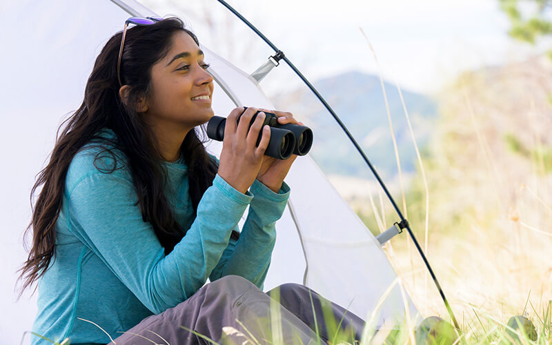 photo of a woman in a tent, holding a pair of PROSTAFF P3 8X42 binoculars