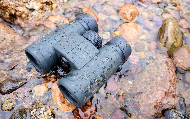 photo of PROSTAFF P3 10X30 binoculars on rocks with water drops