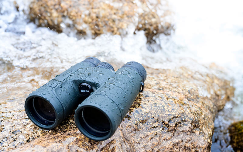 photo of PROSTAFF P7 10x42 binoculars on a rock with water splashing