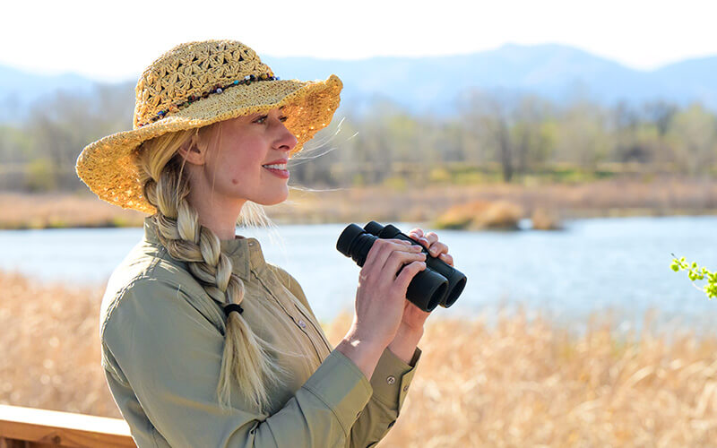 photo of a woman in a hat smiling, with a pair of PROSTAFF P7 10x42 binoculars 