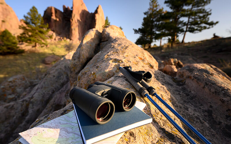 photo of PROSTAFF P7 8x42 binoculars on a rock with hiking equipment