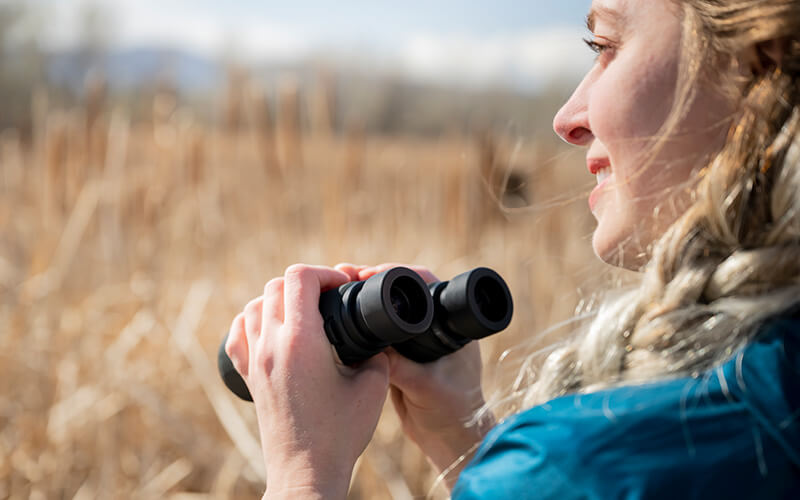photo of a smiling woman in profile holding PROSTAFF P7 8x42 binoculars