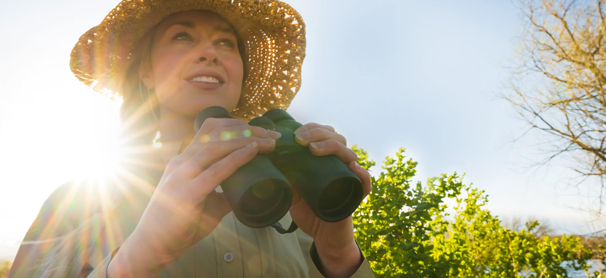 Photo of a woman in a hat holding a pair of PROSTAFF P3 10X42 binoculars