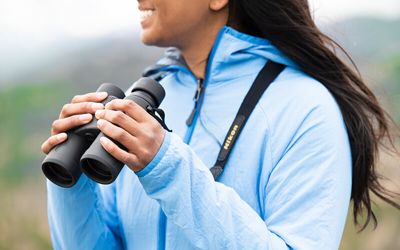 photo of a woman in a hat, holding a pair of PROSTAFF P3 10X42 binoculars