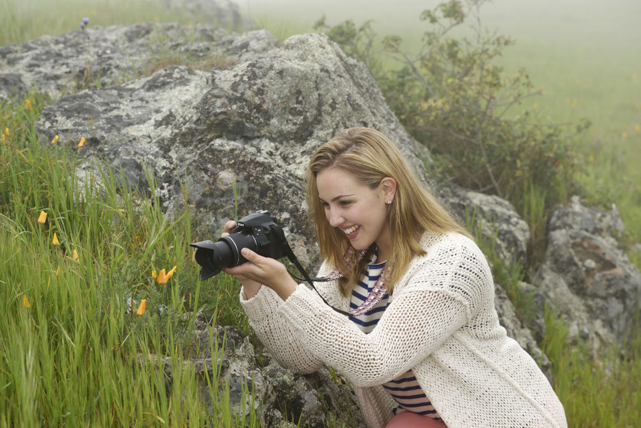 Photo of a woman shooting flowers using the AF-P DX NIKKOR 18-55mm f/3.5-5.6G VR lens on a Nikon DSLR