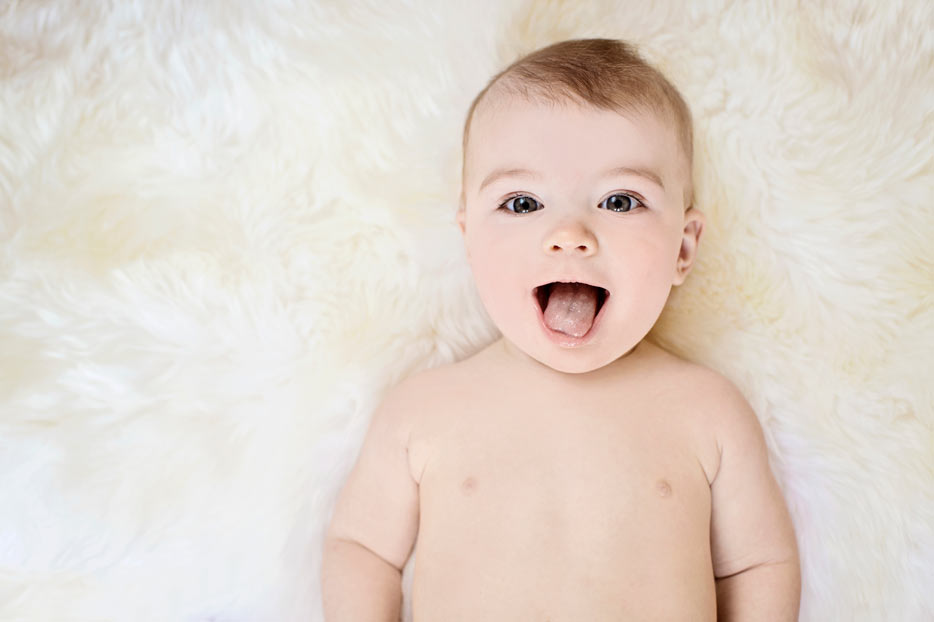 Photo of a baby smiling, lying on a fur blanket shot with the AF-S NIKKOR 35mm f/1.4G